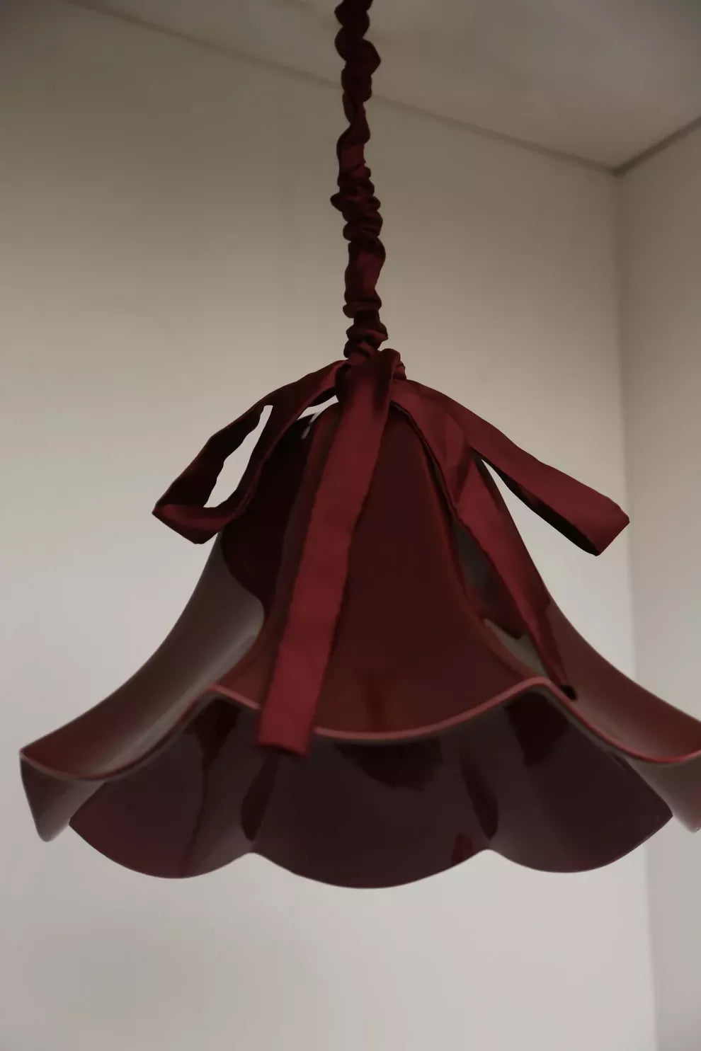 A red, conical pendant light with a glossy finish and a silk satin cord cover,  available  to buy on the-salon.com. SALON curates the finest , unique, handmade pieces from the interior industry's best makers and brands. Shop luxury furniture, lighting, rugs, art, antiques and vintage pieces and accessories from SALON interior designed rooms.