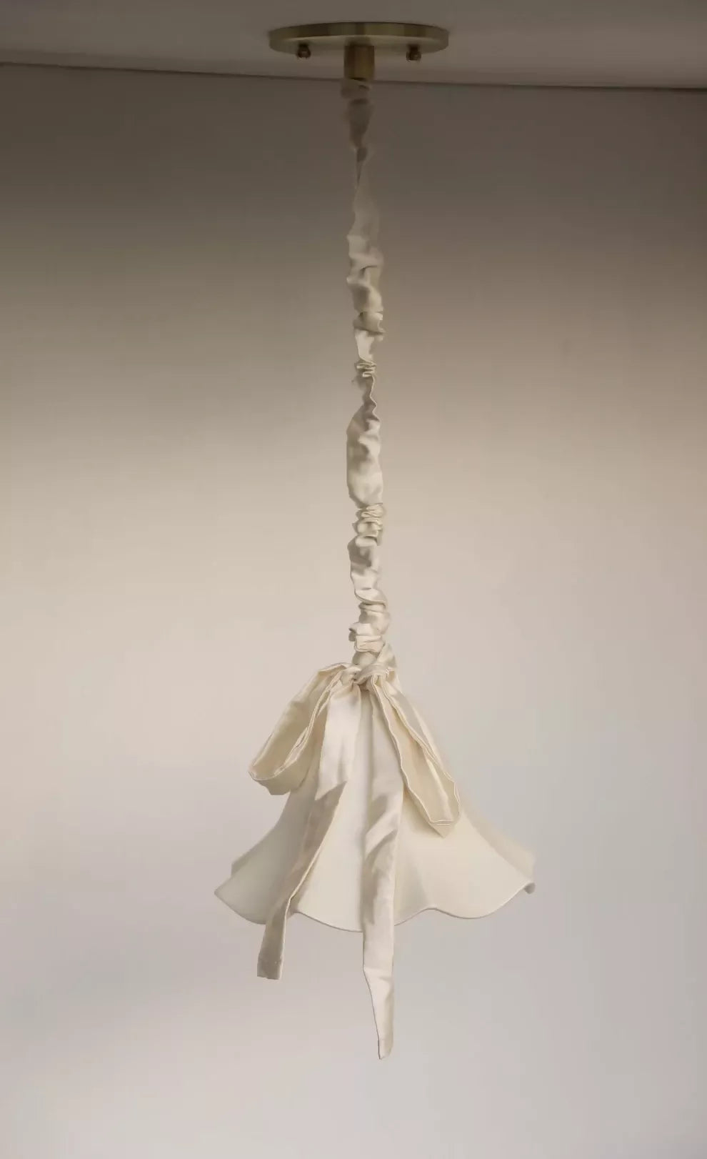 A white, conical pendant light with a glossy finish and a silk satin cord cover,  available  to buy on the-salon.com. SALON curates the finest , unique, handmade pieces from the interior industry's best makers and brands. Shop luxury furniture, lighting, rugs, art, antiques and vintage pieces and accessories from SALON interior designed rooms.