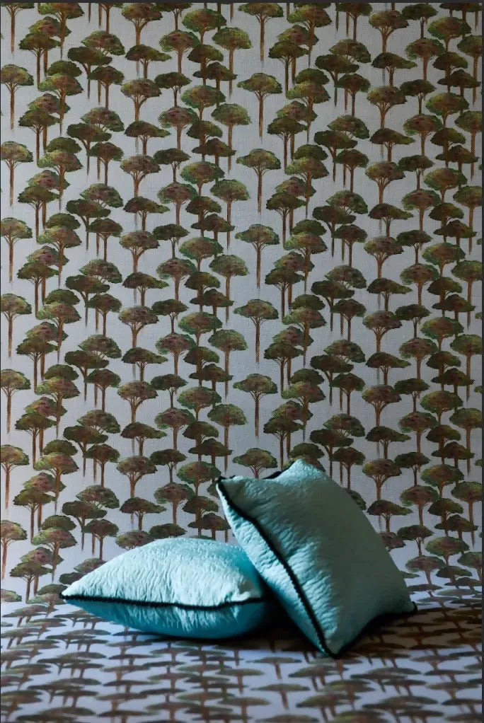 A room with wallpaper featuring a pattern of stylized pine trees and umbrellas in green shades, with two cushions in the foreground,available  to buy on the-salon.com. SALON curates the finest , unique, handmade pieces from the interior industry's best makers and brands. Shop luxury furniture, lighting, rugs, art, antiques and vintage pieces and accessories from SALON interior designed rooms.