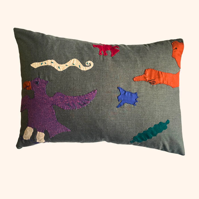 A rectangular cushion with a geometric pattern featuring abstract characters in various colors on a gray background,  available  to buy on the-salon.com. SALON curates the finest , unique, handmade pieces from the interior industry's best makers and brands. Shop luxury furniture, lighting, rugs, art, antiques and vintage pieces and accessories from SALON interior designed rooms.
