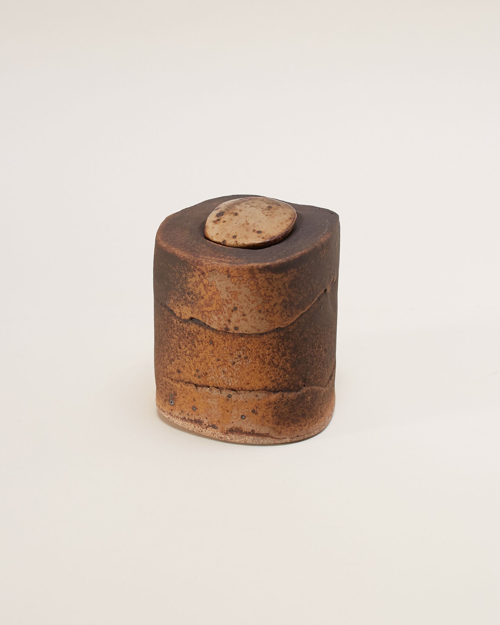 A hand-built ceramic box with a naively formed mushroom shaped lid and a speckled glaze in deep black-brown to ochre and sandy tones,  available  to buy on the-salon.com. SALON curates the finest , unique, handmade pieces from the interior industry's best makers and brands. Shop luxury furniture, lighting, rugs, art, antiques and vintage pieces and accessories from SALON interior designed rooms.