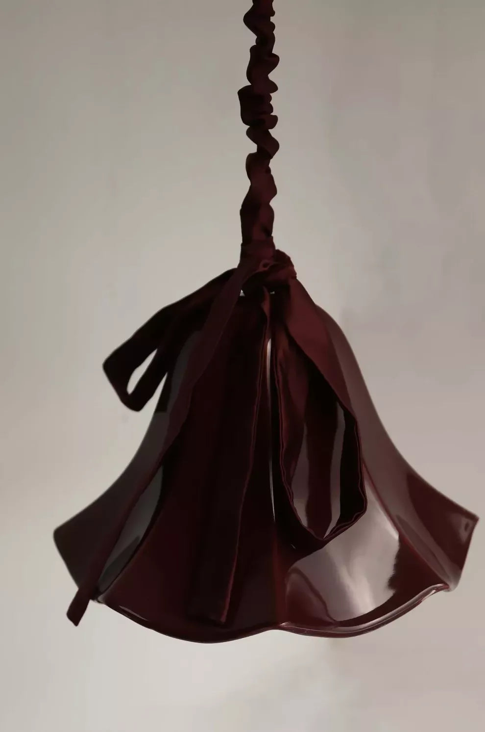 A red, conical pendant light with a glossy finish and a silk satin cord cover,  available  to buy on the-salon.com. SALON curates the finest , unique, handmade pieces from the interior industry's best makers and brands. Shop luxury furniture, lighting, rugs, art, antiques and vintage pieces and accessories from SALON interior designed rooms.