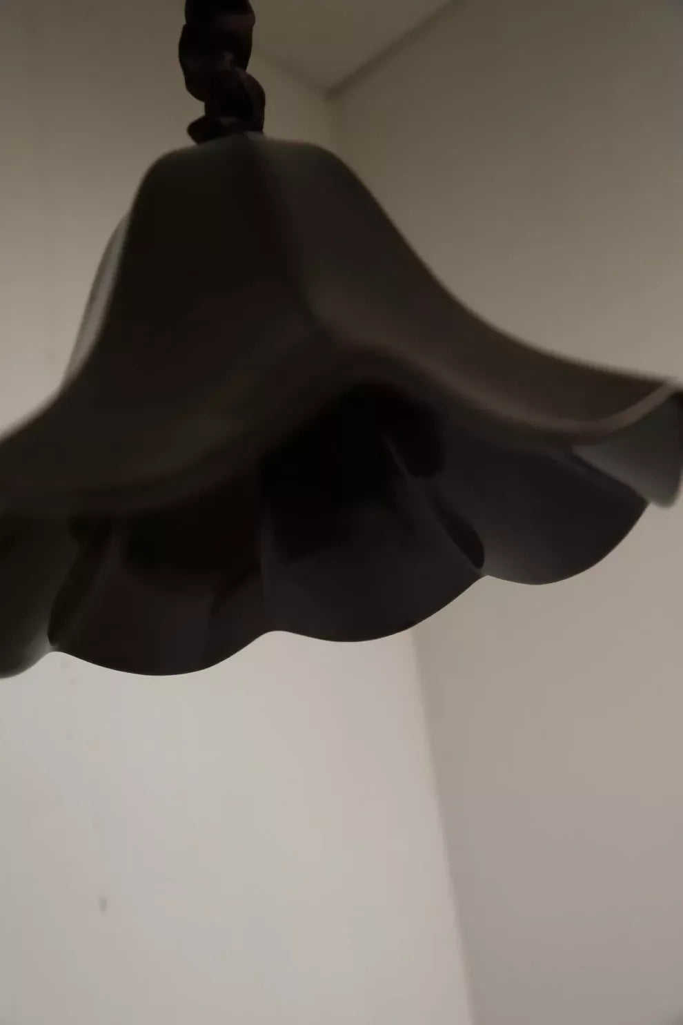 A black, conical pendant light with a glossy finish and a silk satin cord cover,  available  to buy on the-salon.com. SALON curates the finest , unique, handmade pieces from the interior industry's best makers and brands. Shop luxury furniture, lighting, rugs, art, antiques and vintage pieces and accessories from SALON interior designed rooms.
