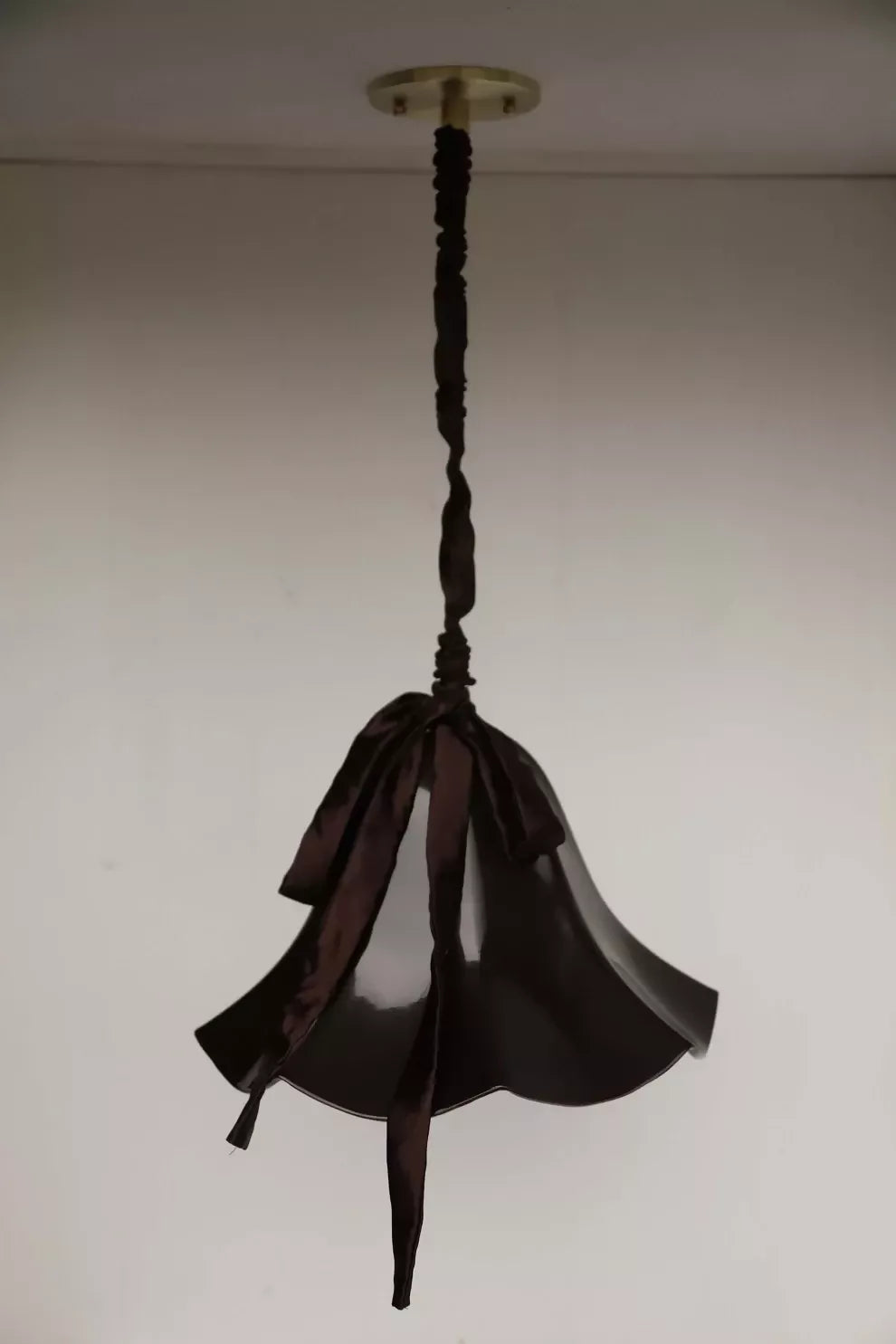 A brown, conical pendant light with a glossy finish and a silk satin cord cover,  available  to buy on the-salon.com. SALON curates the finest , unique, handmade pieces from the interior industry's best makers and brands. Shop luxury furniture, lighting, rugs, art, antiques and vintage pieces and accessories from SALON interior designed rooms.