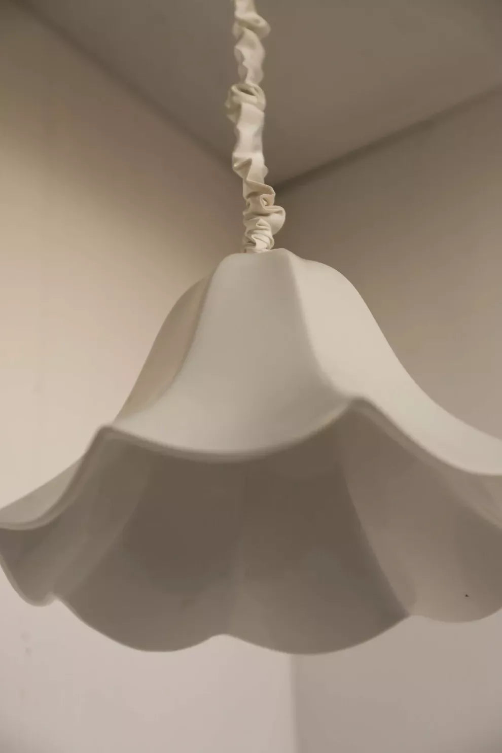 A white, conical pendant light with a glossy finish and a silk satin cord cover,  available  to buy on the-salon.com. SALON curates the finest , unique, handmade pieces from the interior industry's best makers and brands. Shop luxury furniture, lighting, rugs, art, antiques and vintage pieces and accessories from SALON interior designed rooms.