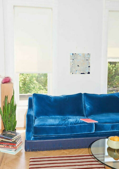 A blue velvet sofa with plush seats and a tasseled fringe, named 'Large Atlanta Sofa by Orior', available  to buy on the-salon.com. SALON curates the finest , unique, handmade pieces from the interior industry's best makers and brands. Shop luxury furniture, lighting, rugs, art, antiques and vintage pieces and accessories from SALON interior designed rooms.