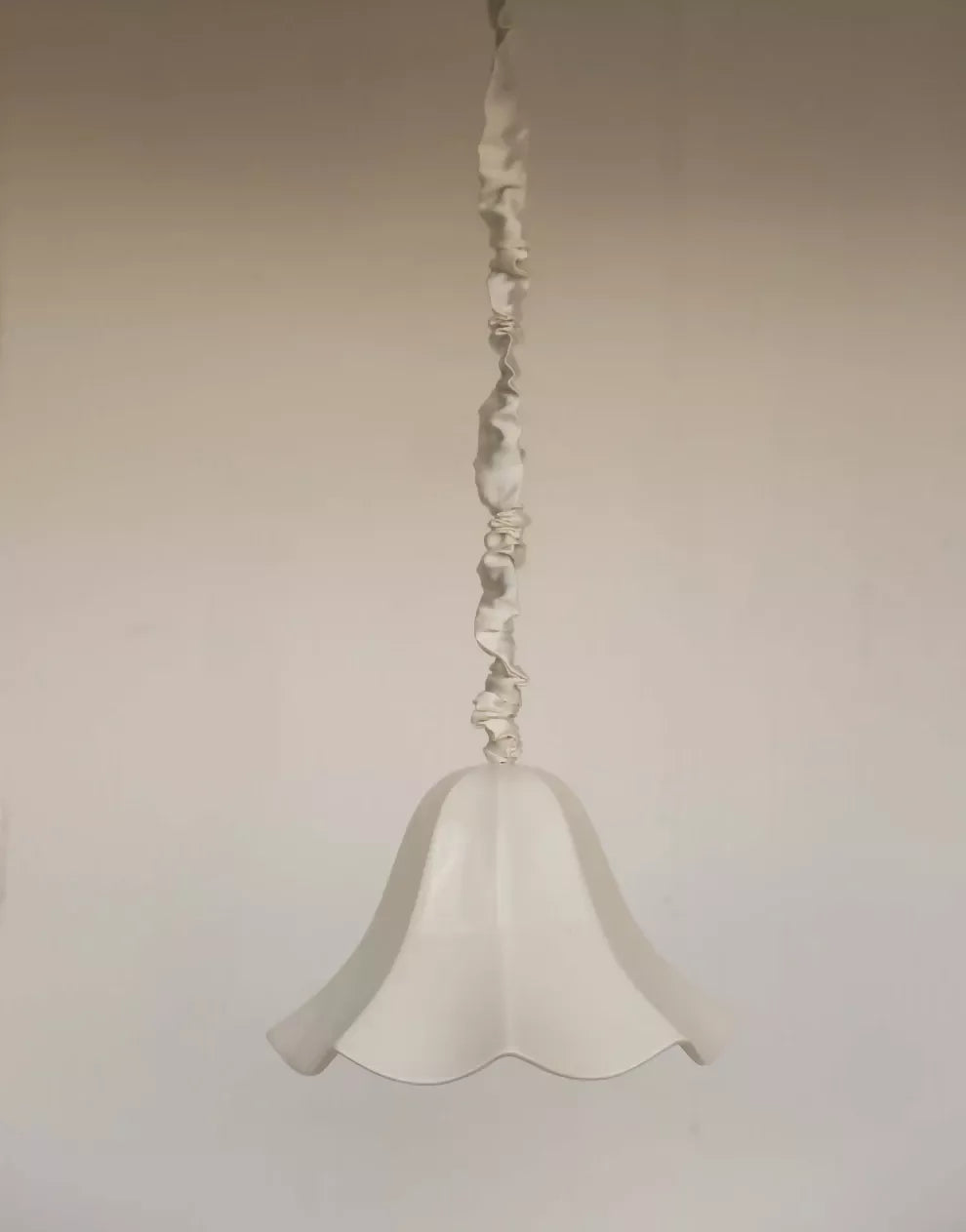 A white, conical pendant light with a glossy finish and a silk satin cord cover,  available  to buy on the-salon.com. SALON curates the finest , unique, handmade pieces from the interior industry's best makers and brands. Shop luxury furniture, lighting, rugs, art, antiques and vintage pieces and accessories from SALON interior designed rooms.