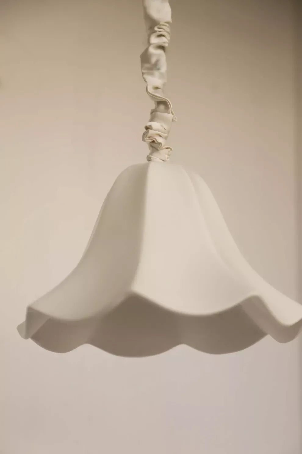 A white, conical pendant light with a glossy finish and a silk satin cord cover,  available  to buy on the-salon.com. SALON curates the finest , unique, handmade pieces from the interior industry's best makers and brands. Shop luxury furniture, lighting, rugs, art, antiques and vintage pieces and accessories from SALON interior designed rooms.