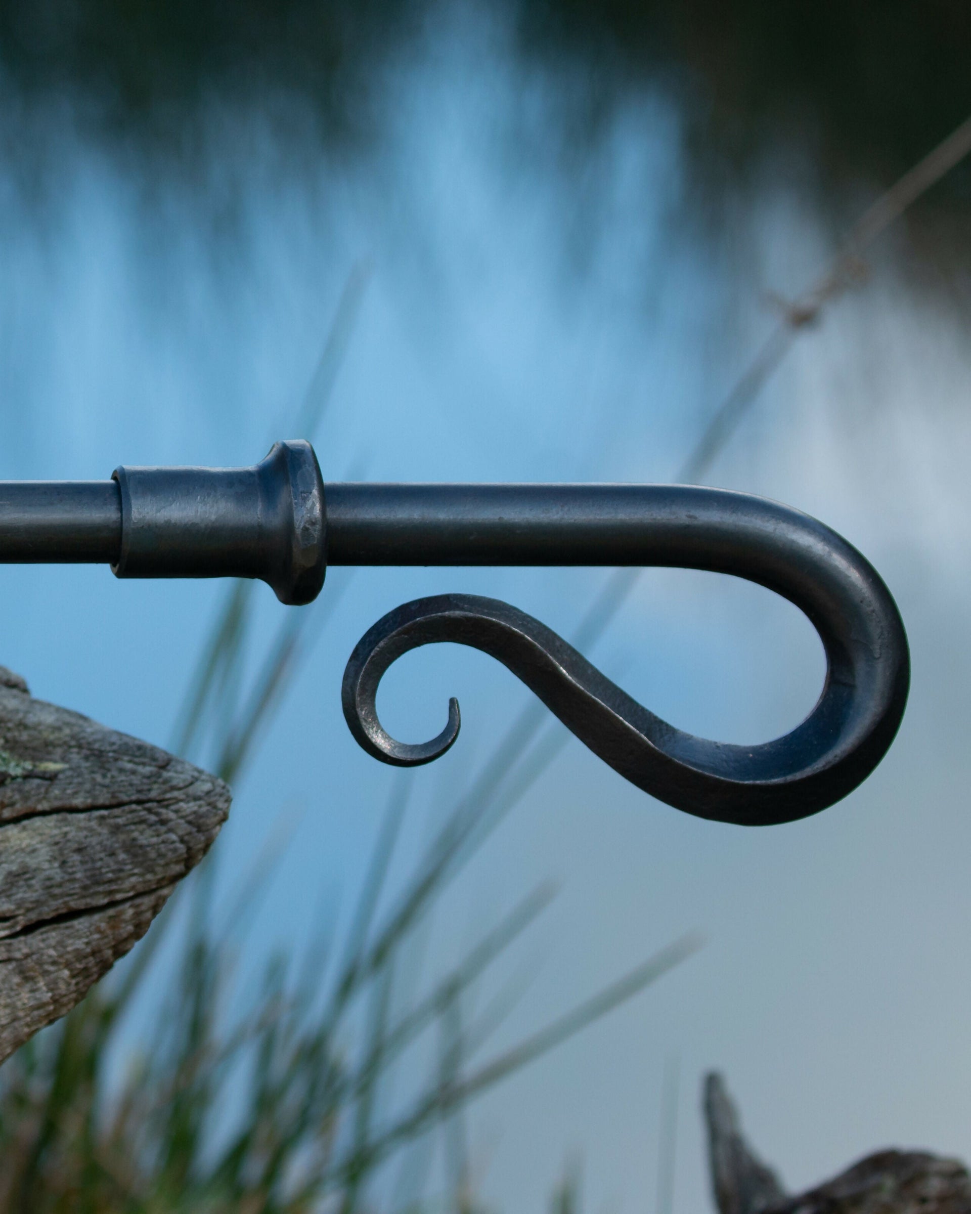 A close-up of a solid wrought iron curtain pole with a hand forged shepherd's crook finial, available  to buy on the-salon.com. SALON curates the finest , unique, handmade pieces from the interior industry's best makers and brands. Shop luxury furniture, lighting, rugs, art, antiques and vintage pieces and accessories from SALON interior designed room