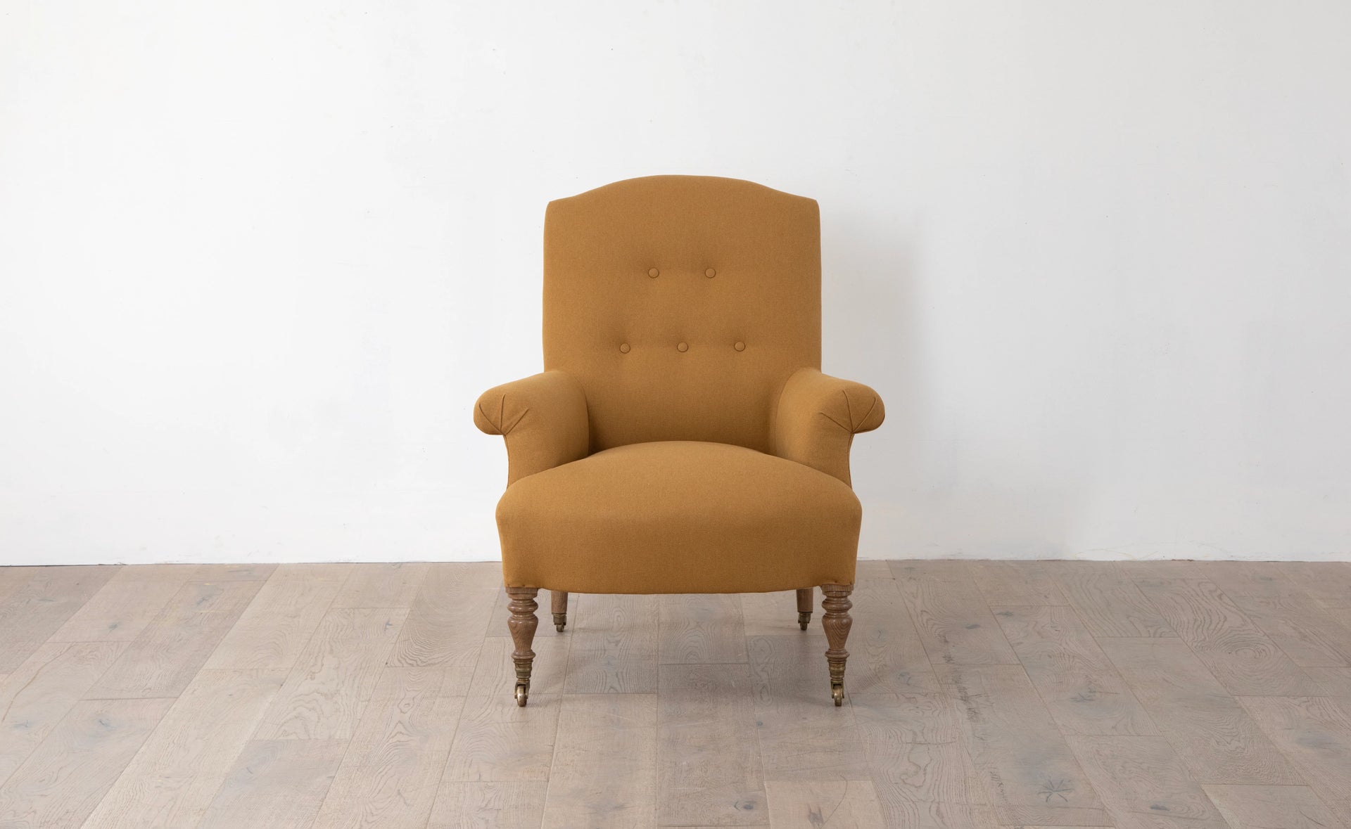 A brown upholstered armchair with button back detailing and scroll arms, set against a white background,  available  to buy on the-salon.com. SALON curates the finest , unique, handmade pieces from the interior industry's best makers and brands. Shop luxury furniture, lighting, rugs, art, antiques and vintage pieces and accessories from SALON interior designed rooms.