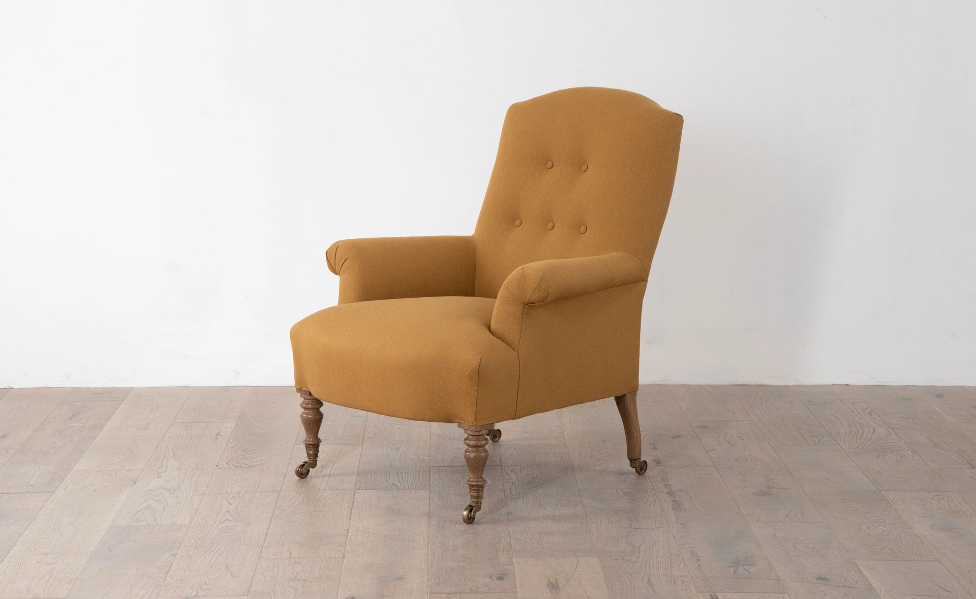 A brown upholstered armchair with button back detailing and scroll arms, set against a white background,  available  to buy on the-salon.com. SALON curates the finest , unique, handmade pieces from the interior industry's best makers and brands. Shop luxury furniture, lighting, rugs, art, antiques and vintage pieces and accessories from SALON interior designed rooms.