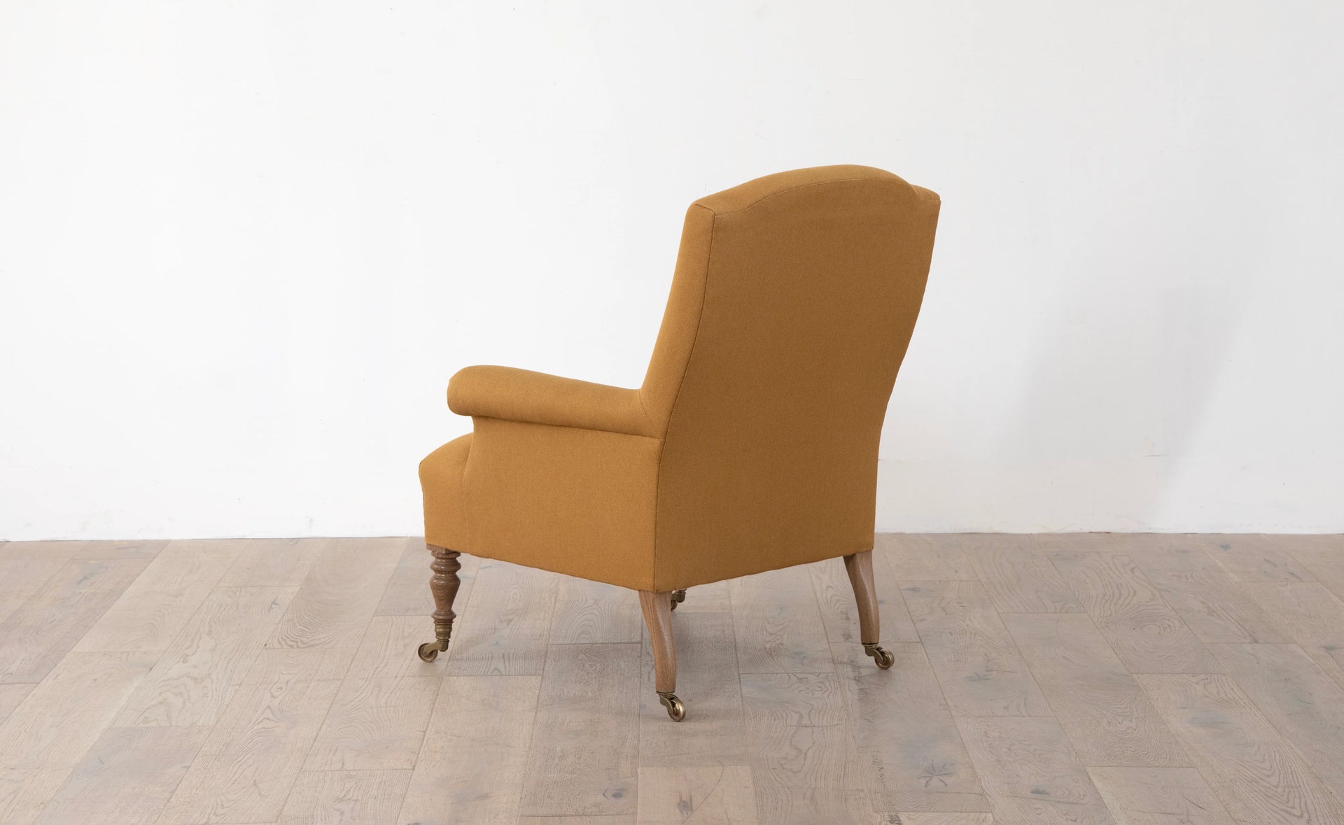 A brown upholstered armchair with button back detailing and scroll arms, set against a white background,  available  to buy on the-salon.com. SALON curates the finest , unique, handmade pieces from the interior industry's best makers and brands. Shop luxury furniture, lighting, rugs, art, antiques and vintage pieces and accessories from SALON interior designed rooms.