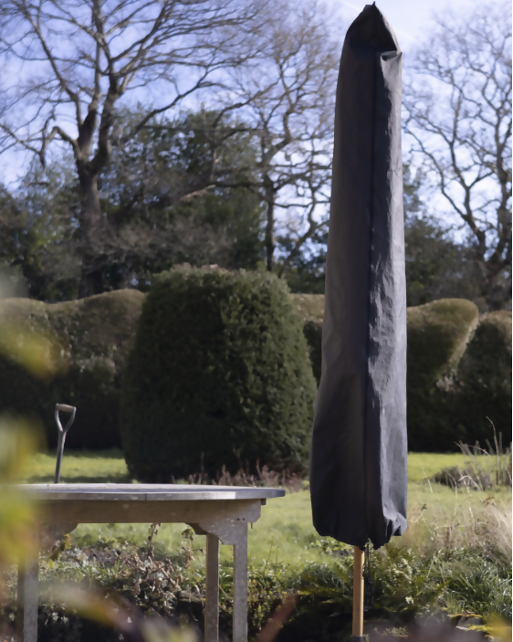 Black umbrella cover on a stand in a garden setting with trees and shrubs.