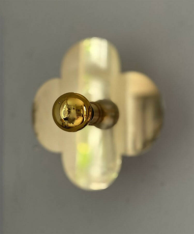 A wall light fixture with a gold-colored top and clear, possibly glass or acrylic, quatrefoil-shaped base,  available  to buy on the-salon.com. SALON curates the finest , unique, handmade pieces from the interior industry's best makers and brands. Shop luxury furniture, lighting, rugs, art, antiques and vintage pieces and accessories from SALON interior designed rooms.