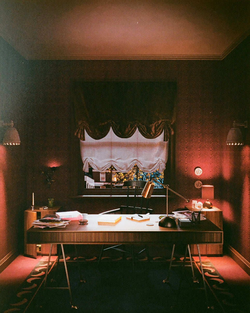 Vintage-style room with desk, lamp, and window with curtain.