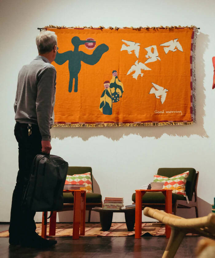 A colourful throw blanket featuring an illustration of a bird, an ostrich, and a jackal in a whimsical morning scene with the text 'Good morning' at the bottom,  available  to buy on the-salon.com. SALON curates the finest , unique, handmade pieces from the interior industry's best makers and brands. Shop luxury furniture, lighting, rugs, art, antiques and vintage pieces and accessories from SALON interior designed rooms.