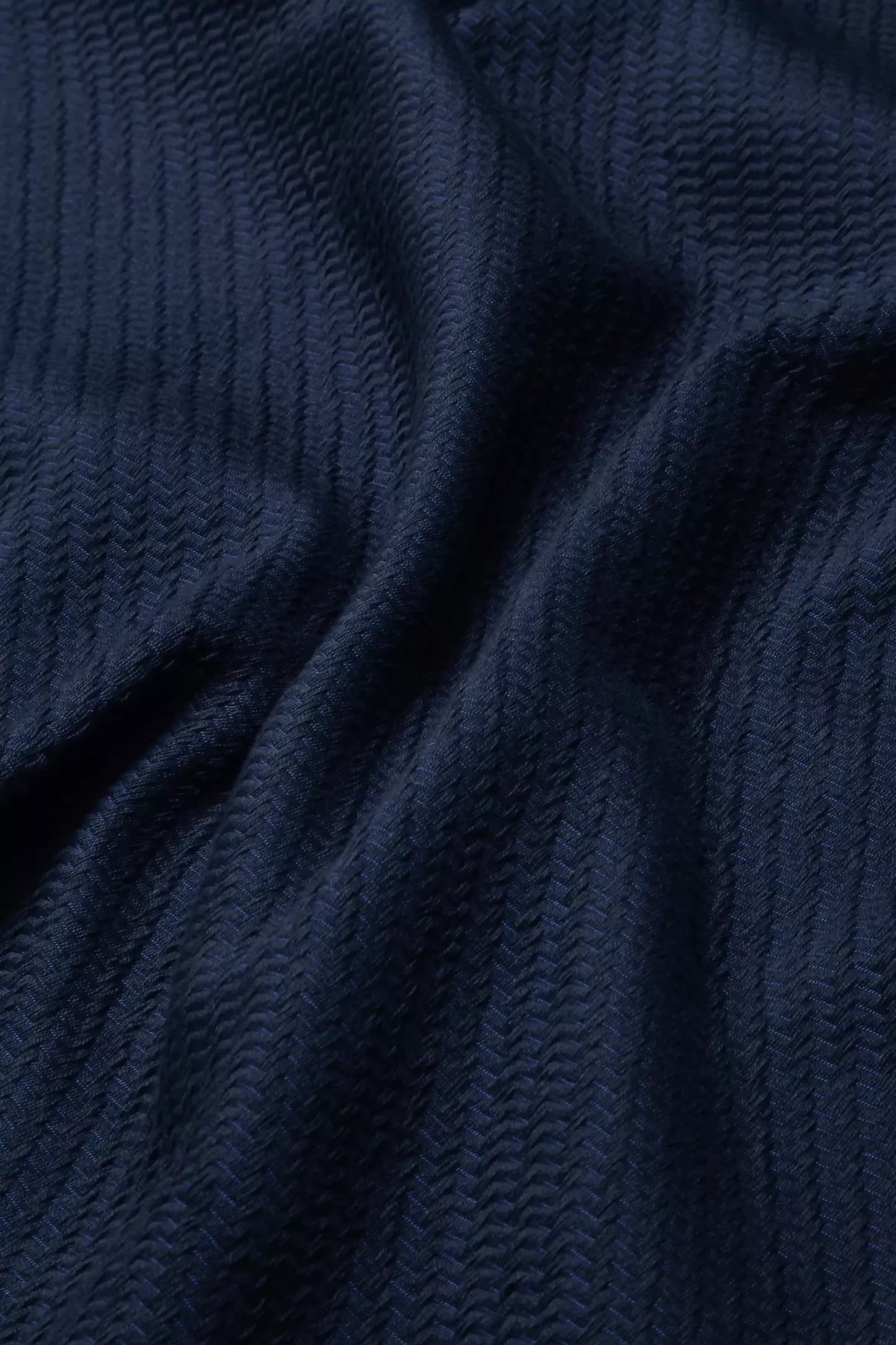 Close-up view of a navy blue fabric with a textured weave pattern,  available  to buy on the-salon.com. SALON curates the finest , unique, handmade pieces from the interior industry's best makers and brands. Shop luxury furniture, lighting, rugs, art, antiques and vintage pieces and accessories from SALON interior designed rooms.
