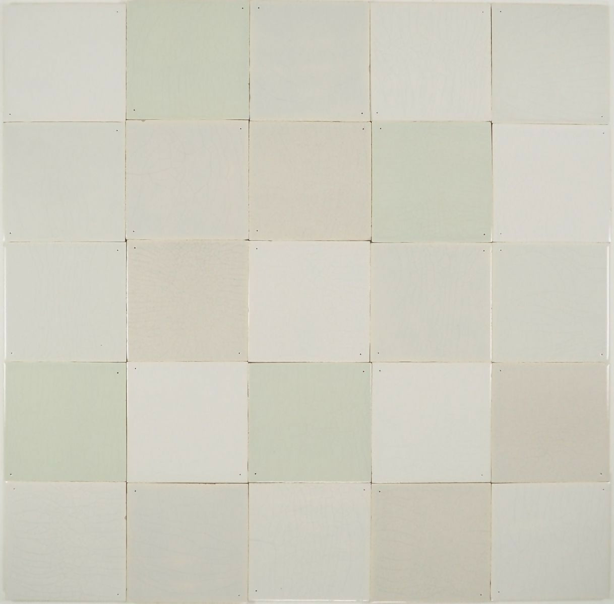 A grid of square Delft tiles in white, grey, and green shades, some with pinholes and a crackled finish, others without enhancements,  available  to buy on the-salon.com. SALON curates the finest , unique, handmade pieces from the interior industry's best makers and brands. Shop luxury furniture, lighting, rugs, art, antiques and vintage pieces and accessories from SALON interior designed rooms.