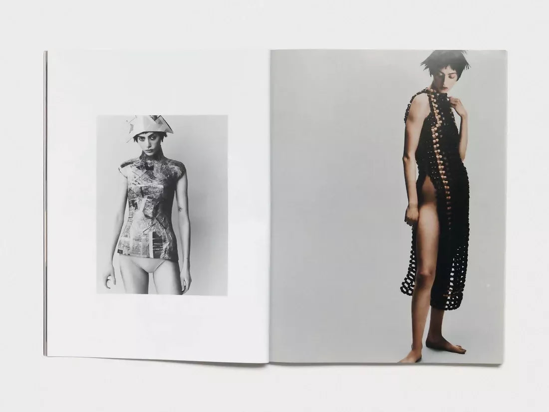 Open book, pages turned to two images. The first one being a woman wearing newspaper clothes moulded for her body and no bottoms, the other being the same woman but now in a black object dress, available  to buy on the-salon.com. SALON curates the finest , unique, handmade pieces from the interior industry's best makers and brands. Shop luxury furniture, lighting, rugs, art, antiques and vintage pieces and accessories from SALON interior designed rooms.