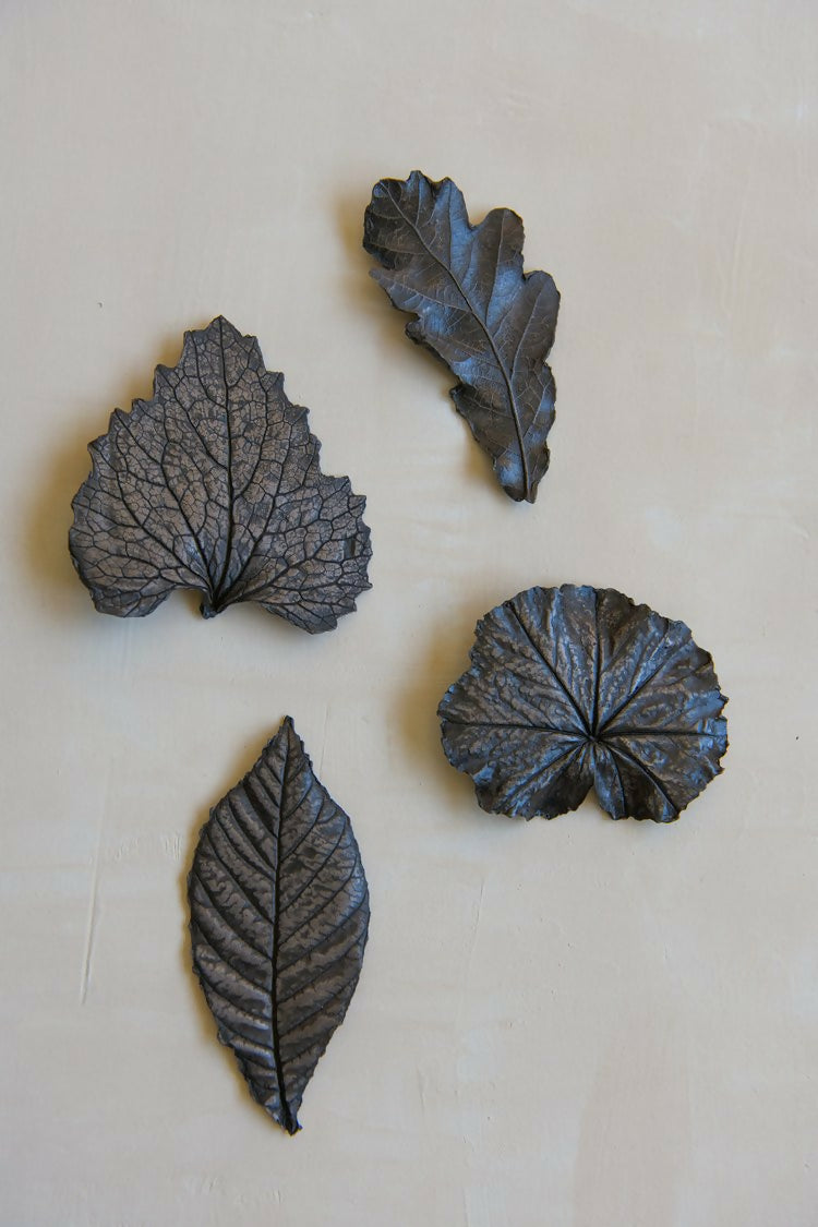 A collection of bronze leaf-shaped sculptures at various angles on a light background, available  to buy on the-salon.com. SALON curates the finest , unique, handmade pieces from the interior industry's best makers and brands. Shop luxury furniture, lighting, rugs, art, antiques and vintage pieces and accessories from SALON interior designed rooms.