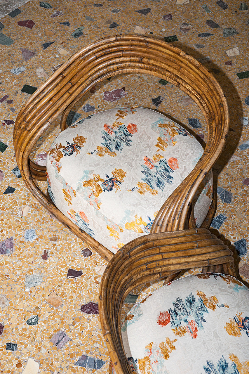 An image of a piece of fabric with yellow, blue and pink colours on a white lace background, being used as upholstery on chairs, available  to buy on the-salon.com. SALON curates the finest , unique, handmade pieces from the interior industry's best makers and brands. Shop luxury furniture, lighting, rugs, art, antiques and vintage pieces and accessories from SALON interior designed rooms.