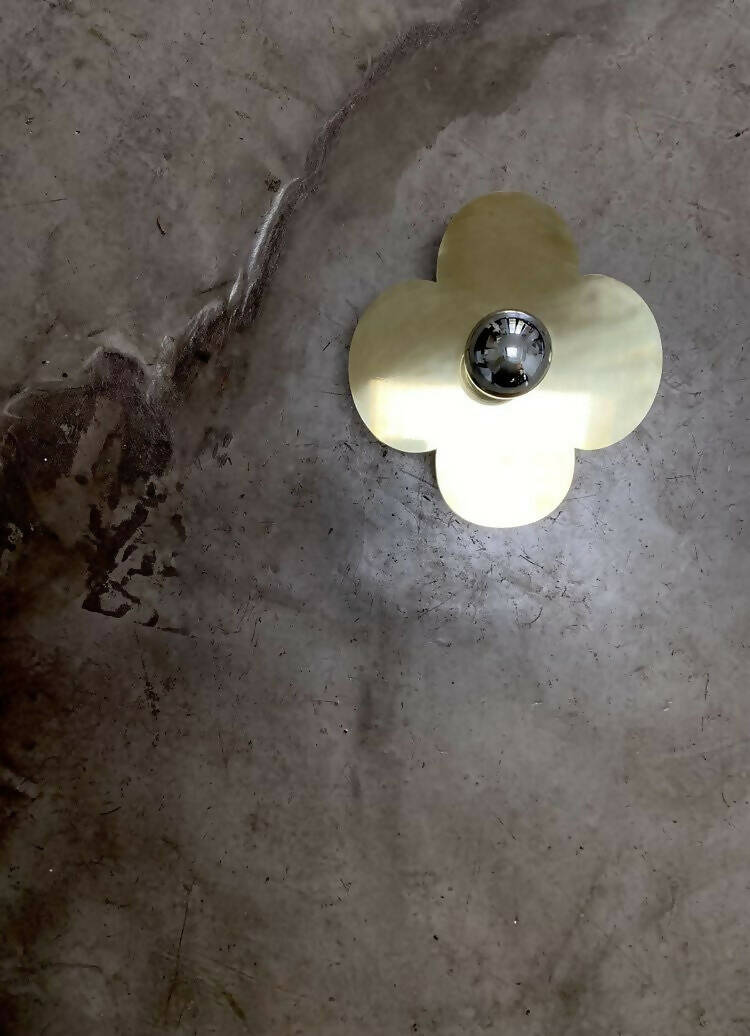 A wall light fixture with a silver-colored top and clear, possibly glass or acrylic, quatrefoil-shaped base,  available  to buy on the-salon.com. SALON curates the finest , unique, handmade pieces from the interior industry's best makers and brands. Shop luxury furniture, lighting, rugs, art, antiques and vintage pieces and accessories from SALON interior designed rooms.