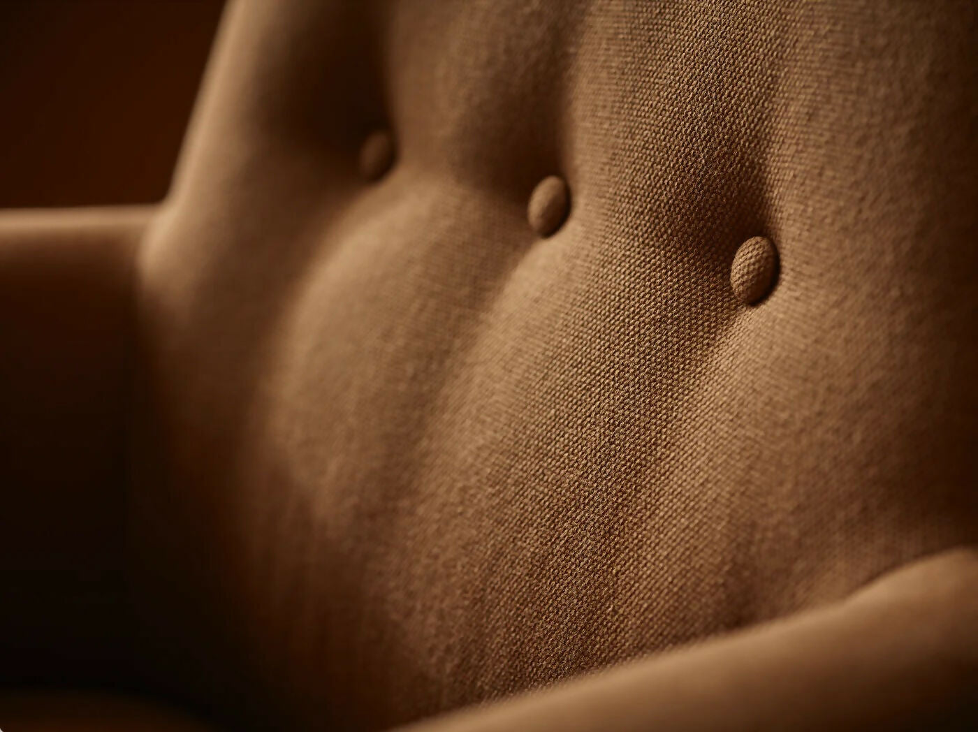 A brown upholstered armchair with button back detailing and scroll arms, set against a wooden panel background,  available  to buy on the-salon.com. SALON curates the finest , unique, handmade pieces from the interior industry's best makers and brands. Shop luxury furniture, lighting, rugs, art, antiques and vintage pieces and accessories from SALON interior designed rooms.