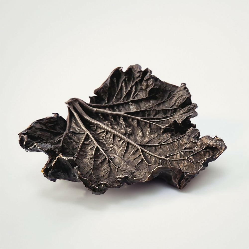 A bronze bowl with a leaf shape, featuring a textured surface and a dark patina finish,  available  to buy on the-salon.com. SALON curates the finest , unique, handmade pieces from the interior industry's best makers and brands. Shop luxury furniture, lighting, rugs, art, antiques and vintage pieces and accessories from SALON interior designed rooms.