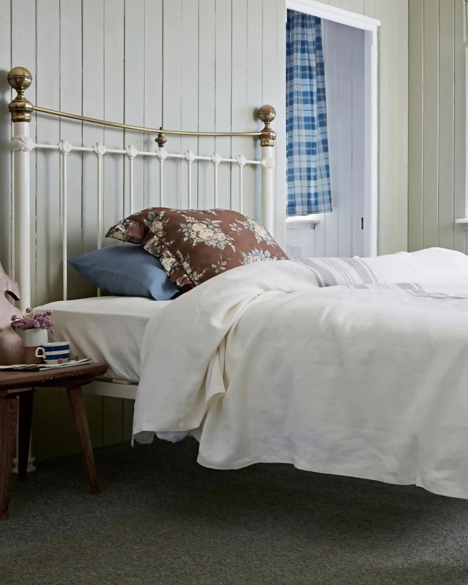 White metal bed with decorative pillows in a bright bedroom