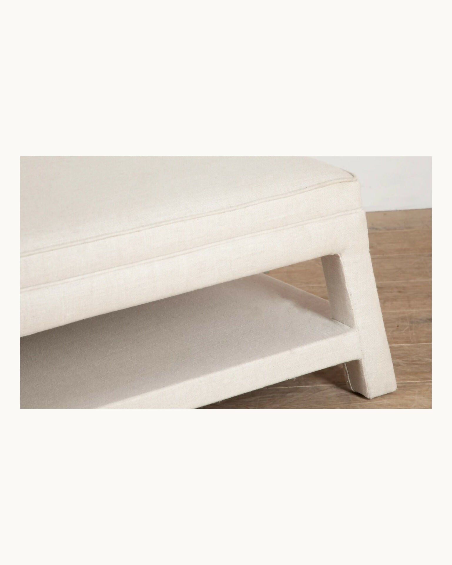 White ottoman on a wooden floor with a white wall background,  available  to buy on the-salon.com. SALON curates the finest , unique, handmade pieces from the interior industry's best makers and brands. Shop luxury furniture, lighting, rugs, art, antiques and vintage pieces and accessories from SALON interior designed rooms.