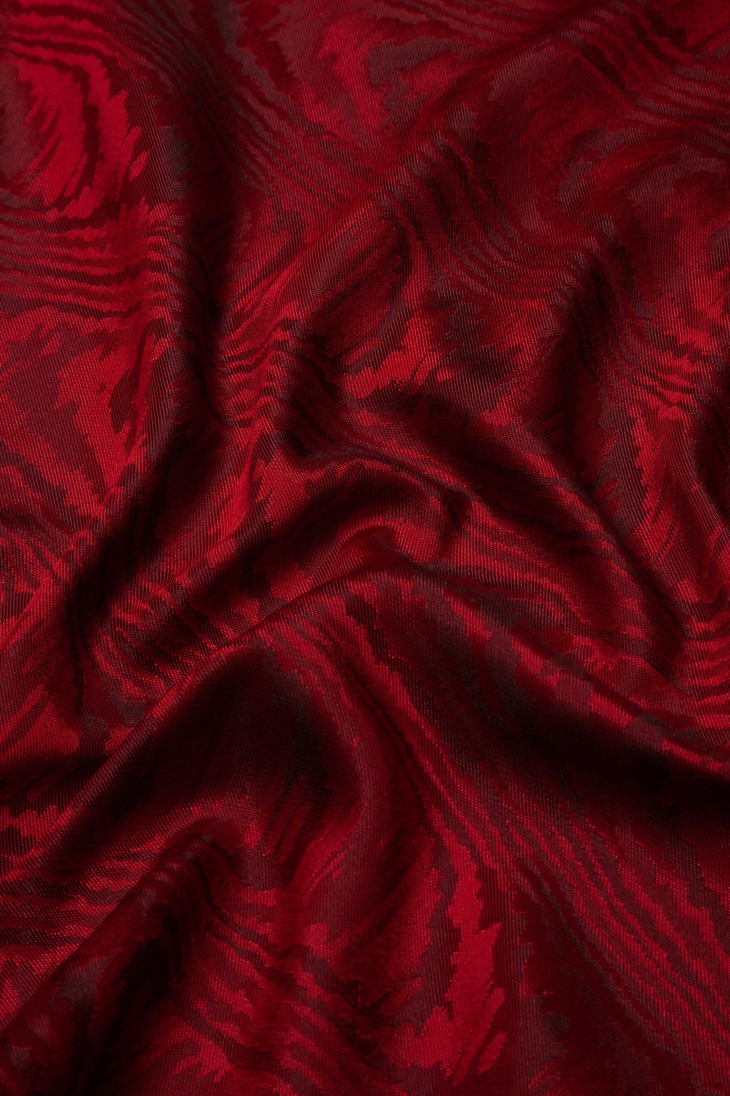 A close-up image of a red moiré patterned fabric,  available  to buy on the-salon.com. SALON curates the finest , unique, handmade pieces from the interior industry's best makers and brands. Shop luxury furniture, lighting, rugs, art, antiques and vintage pieces and accessories from SALON interior designed rooms.