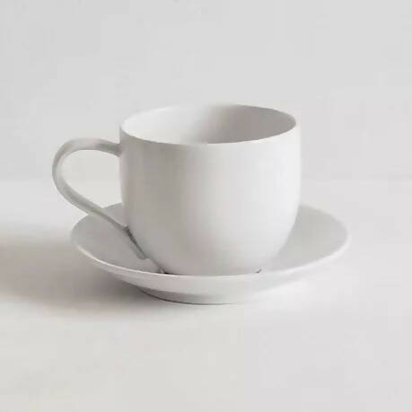 A simple, off-white porcelain mug with a handle, placed against a neutral background , available  to buy on the-salon.com. SALON curates the finest , unique, handmade pieces from the interior industry's best makers and brands. Shop luxury furniture, lighting, rugs, art, antiques and vintage pieces and accessories from SALON interior designed rooms.