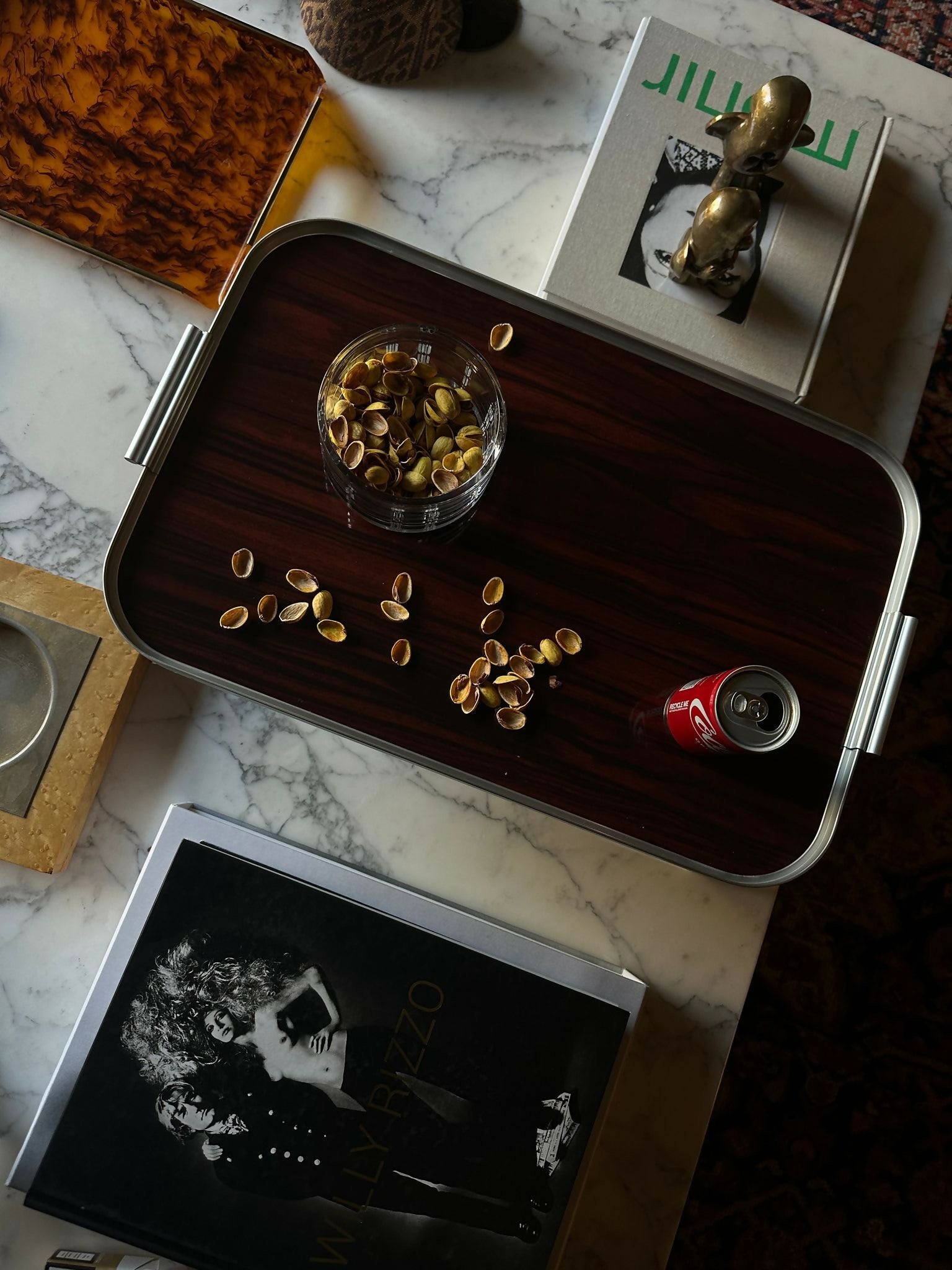 A silver anodised aluminium bed tray with ribbed extruded edge and handle sections, placed on a bed with a book and a glass of water on top, and a can of beverage, available  to buy on the-salon.com. SALON curates the finest , unique, handmade pieces from the interior industry's best makers and brands. Shop luxury furniture, lighting, rugs, art, antiques and vintage pieces and accessories from SALON interior designed rooms.