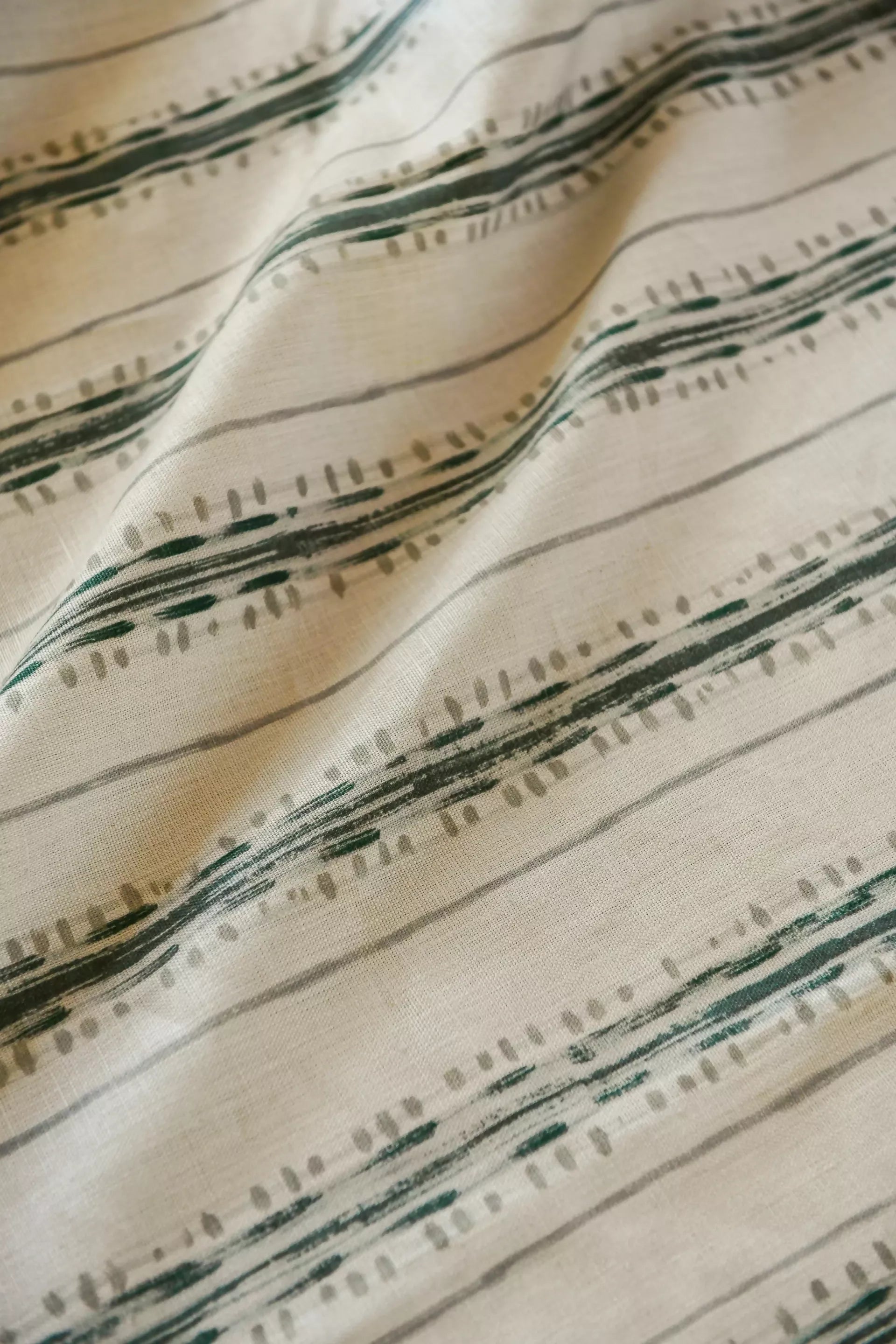 Close-up view of a textile fabric with a striped pattern featuring various shades of green and brown,available  to buy on the-salon.com. SALON curates the finest , unique, handmade pieces from the interior industry's best makers and brands. Shop luxury furniture, lighting, rugs, art, antiques and vintage pieces and accessories from SALON interior designed rooms