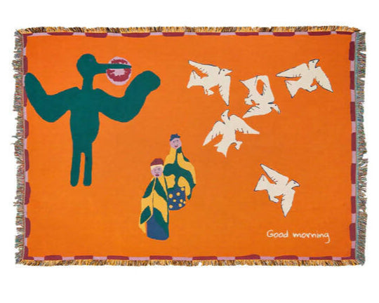 A colourful throw blanket featuring an illustration of a bird, an ostrich, and a jackal in a whimsical morning scene with the text 'Good morning' at the bottom,  available  to buy on the-salon.com. SALON curates the finest , unique, handmade pieces from the interior industry's best makers and brands. Shop luxury furniture, lighting, rugs, art, antiques and vintage pieces and accessories from SALON interior designed rooms.