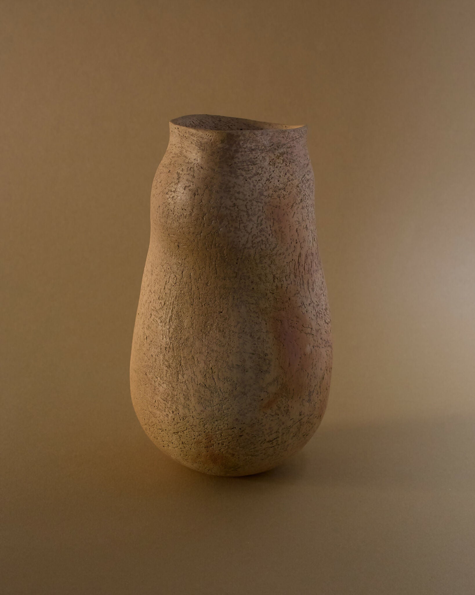 A brown ceramic vase with an organic, irregular silhouette, featuring a smooth yet textured surface with subtle flashes of burnt orange,  available  to buy on the-salon.com. SALON curates the finest , unique, handmade pieces from the interior industry's best makers and brands. Shop luxury furniture, lighting, rugs, art, antiques and vintage pieces and accessories from SALON interior designed rooms.