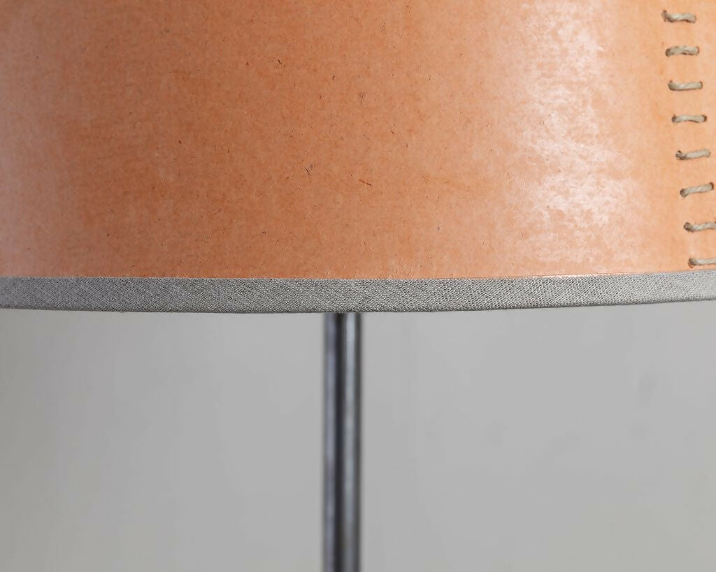 A tapered lampshade with a hand-stitched design, in Pompeian Buff colour, displayed on a stand against a neutral background, available  to buy on the-salon.com. SALON curates the finest , unique, handmade pieces from the interior industry's best makers and brands. Shop luxury furniture, lighting, rugs, art, antiques and vintage pieces and accessories from SALON interior designed rooms.