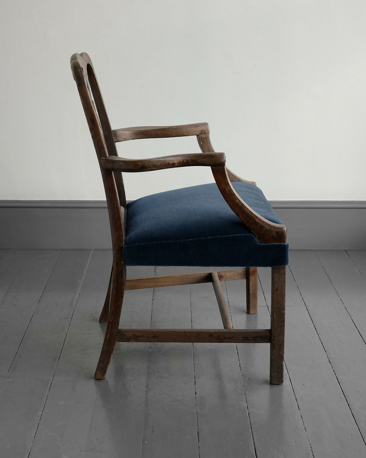 Wooden chair with a blue cushion on a gray floor and white wall background,available to buy from the-salon.com. SALON curates the finest unique handmade pieces from the interior industry's best makers and brands. Shop luxury furniture, lighting, rugs, art, antiques and vintage pieces and accessories from SALON interior designed rooms. 