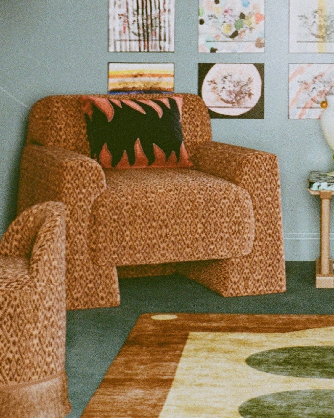 Living room with wicker armchairs, a lamp, and wall art on a green wall.
