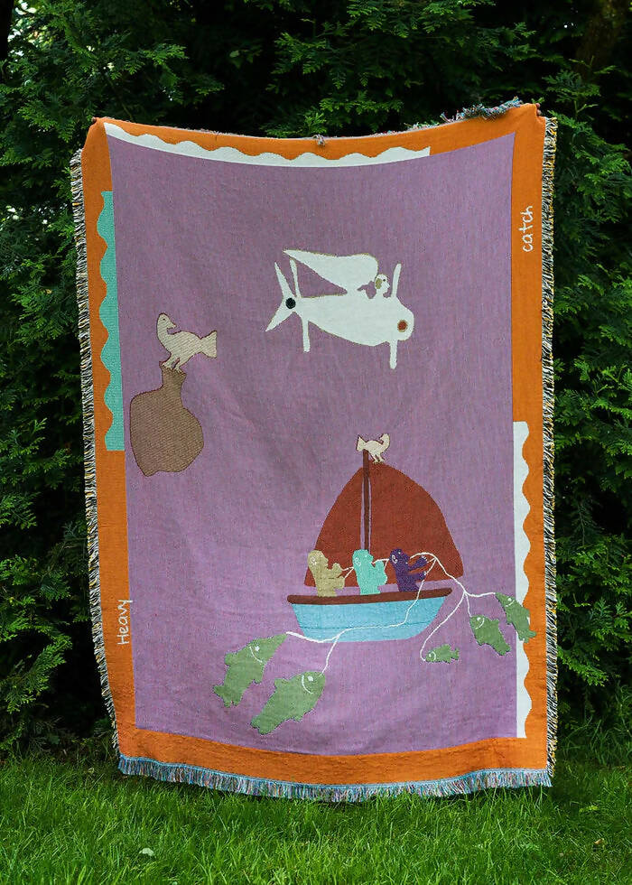 A multicolored throw blanket with a cultural motif hung in the foreground of trees,  available  to buy on the-salon.com. SALON curates the finest , unique, handmade pieces from the interior industry's best makers and brands. Shop luxury furniture, lighting, rugs, art, antiques and vintage pieces and accessories from SALON interior designed rooms.