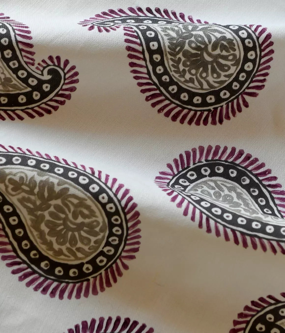 Close-up of a paisley patterned fabric with a design consisting of teardrop shapes and floral elements, predominantly in dark colors on a light background,available  to buy on the-salon.com. SALON curates the finest , unique, handmade pieces from the interior industry's best makers and brands. Shop luxury furniture, lighting, rugs, art, antiques and vintage pieces and accessories from SALON interior designed rooms