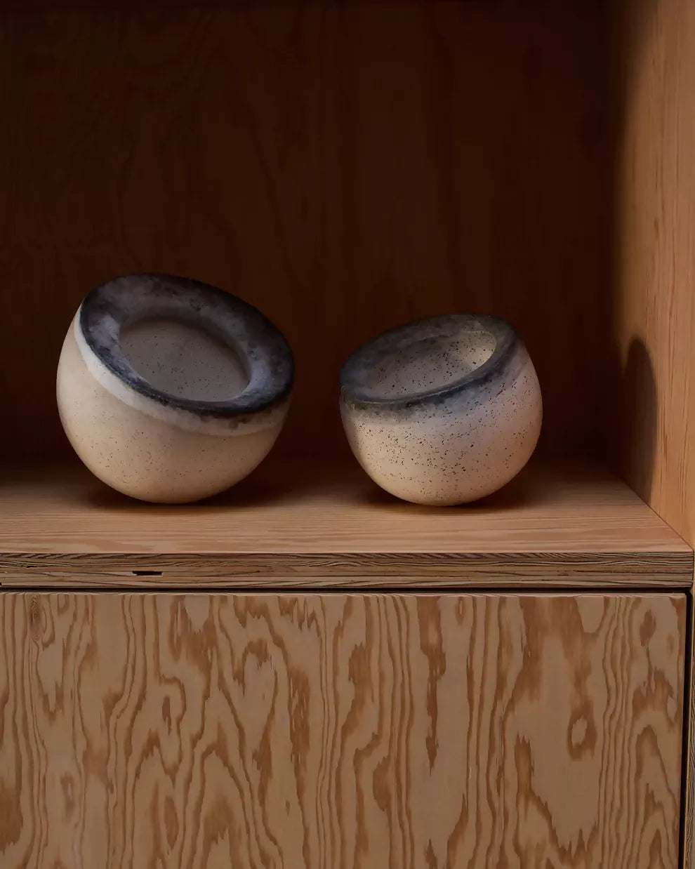 A pair of beige ceramic bowls with a textured surface, one with an open top view and the other with a side view showing the interior,  available  to buy on the-salon.com. SALON curates the finest , unique, handmade pieces from the interior industry's best makers and brands. Shop luxury furniture, lighting, rugs, art, antiques and vintage pieces and accessories from SALON interior designed rooms.