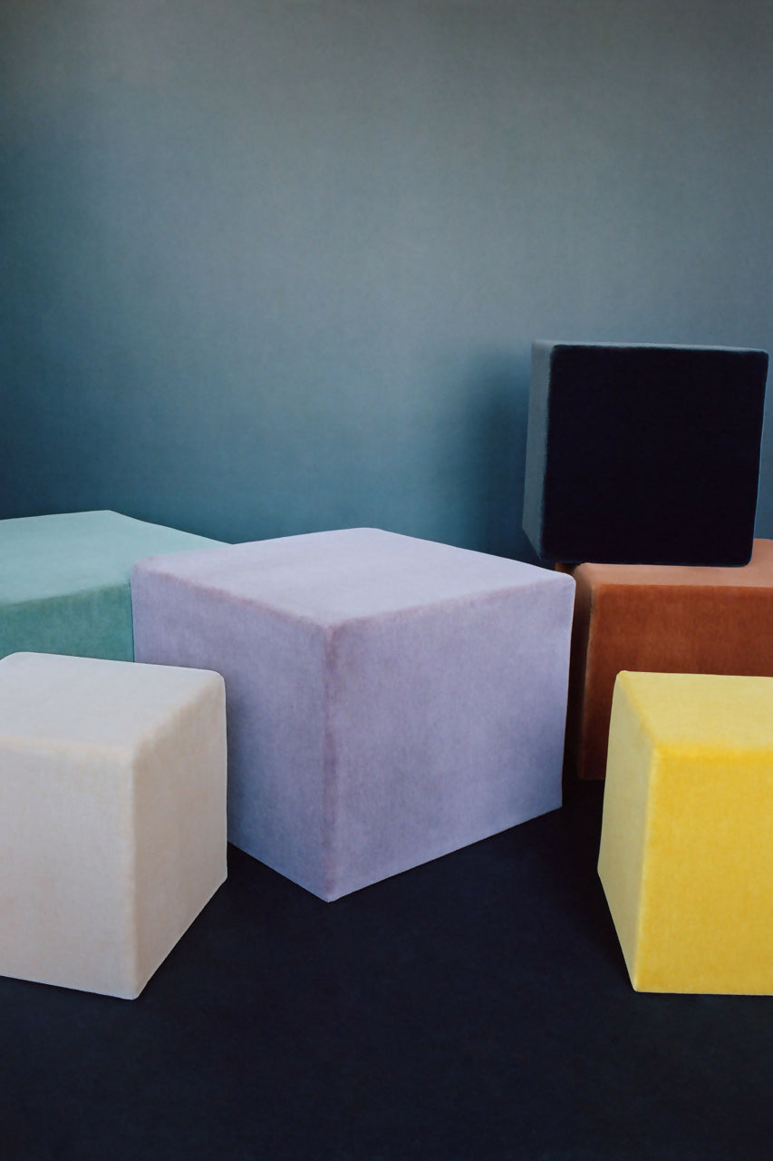 A collection of velvet fabric cubes in various solid colors placed on a surface,  available  to buy on the-salon.com. SALON curates the finest , unique, handmade pieces from the interior industry's best makers and brands. Shop luxury furniture, lighting, rugs, art, antiques and vintage pieces and accessories from SALON interior designed rooms.
