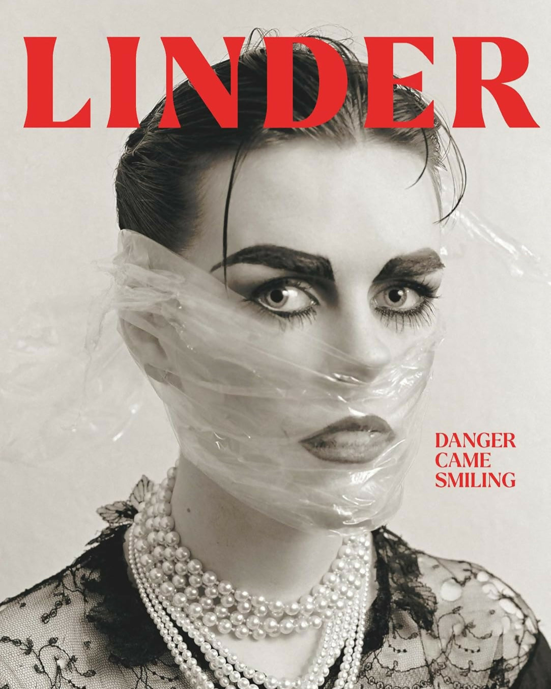 Magazine cover with a woman's face partially covered by plastic wrap, wearing pearls, and the brand 'Linder' displayed,  available  to buy on the-salon.com. SALON curates the finest , unique, handmade pieces from the interior industry's best makers and brands. Shop luxury furniture, lighting, rugs, art, antiques and vintage pieces and accessories from SALON interior designed rooms.