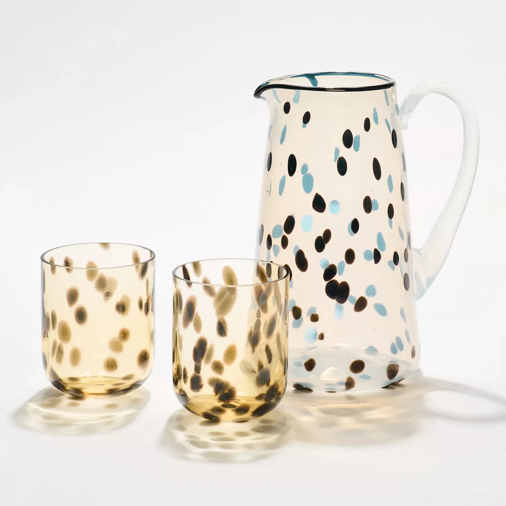 Set of glass tumblers and a pitcher with a polka dot pattern on a white background- available  to buy on the-salon.com. SALON curates the finest , unique, handmade pieces from the interior industry's best makers and brands. Shop luxury furniture, lighting, rugs, art, antiques and vintage pieces and accessories from SALON interior designed rooms.