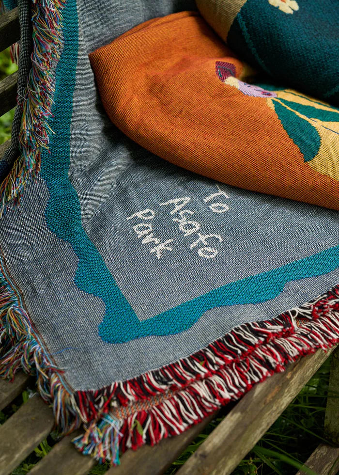 A colorful handcrafted blanket with animal and imaginative figures displayed on a wall, titled 'To ASAFO PARK THROW BLANKET BY AMECHI',  available  to buy on the-salon.com. SALON curates the finest , unique, handmade pieces from the interior industry's best makers and brands. Shop luxury furniture, lighting, rugs, art, antiques and vintage pieces and accessories from SALON interior designed rooms.