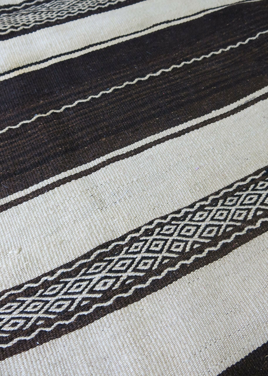 A traditional Moroccan Berber kilim rug with dark brown and cream stripes, featuring intricate embroidery,  available  to buy on the-salon.com. SALON curates the finest , unique, handmade pieces from the interior industry's best makers and brands. Shop luxury furniture, lighting, rugs, art, antiques and vintage pieces and accessories from SALON interior designed rooms.