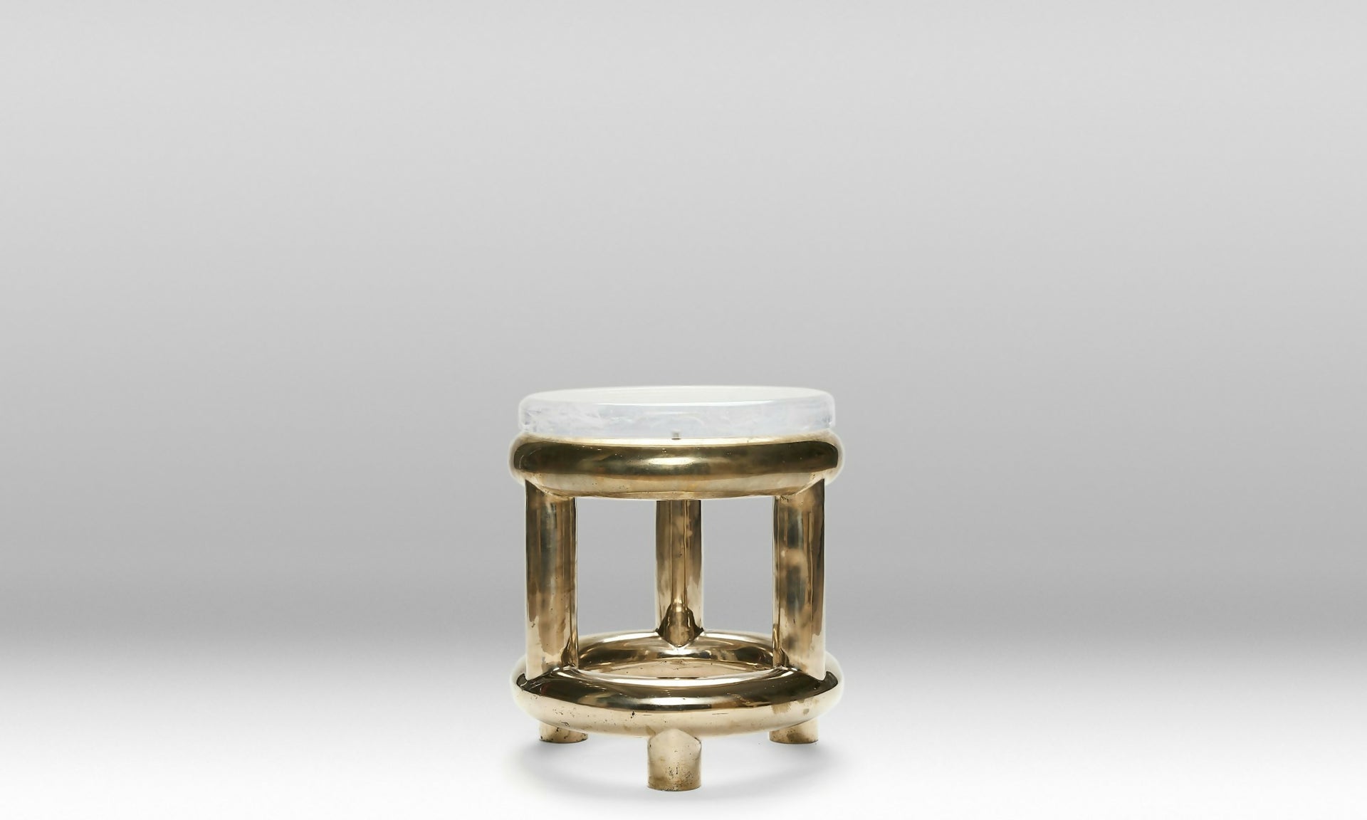 Small stool with gold base and white top on a gray background ,available to buy from the-salon.com. SALON curates the finest unique handmade pieces from the interior industry's best makers and brands. Shop luxury furniture, lighting, rugs, art, antiques and vintage pieces and accessories from SALON interior designed rooms. 