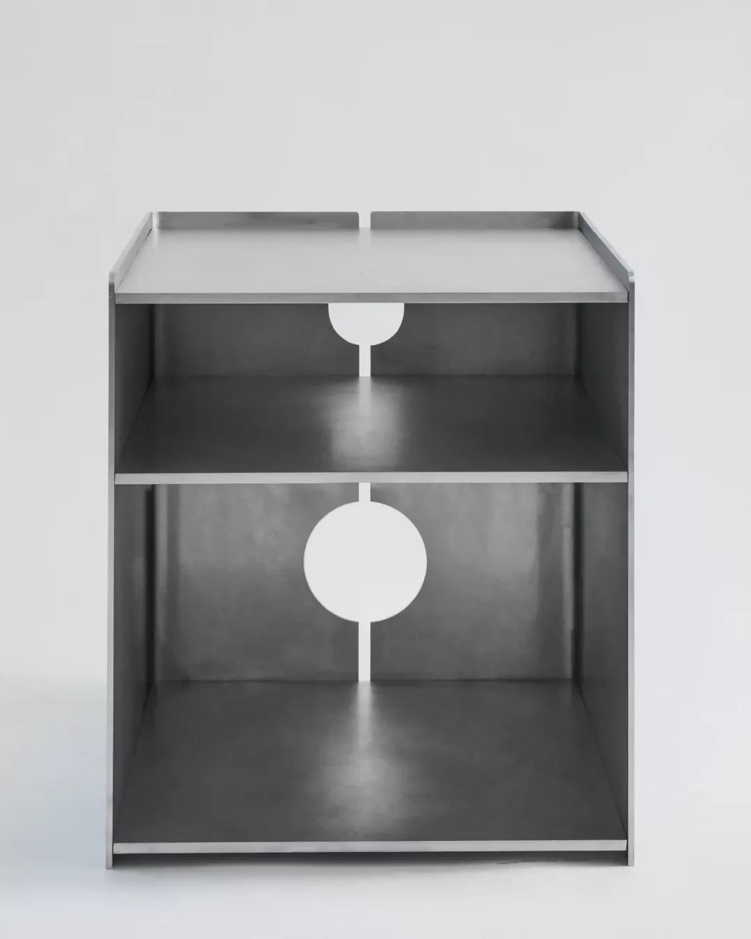 A minimalist silver aluminum media storage cabinet with a hole in the center and multiple shelves,  available  to buy on the-salon.com. SALON curates the finest , unique, handmade pieces from the interior industry's best makers and brands. Shop luxury furniture, lighting, rugs, art, antiques and vintage pieces and accessories from SALON interior designed rooms.