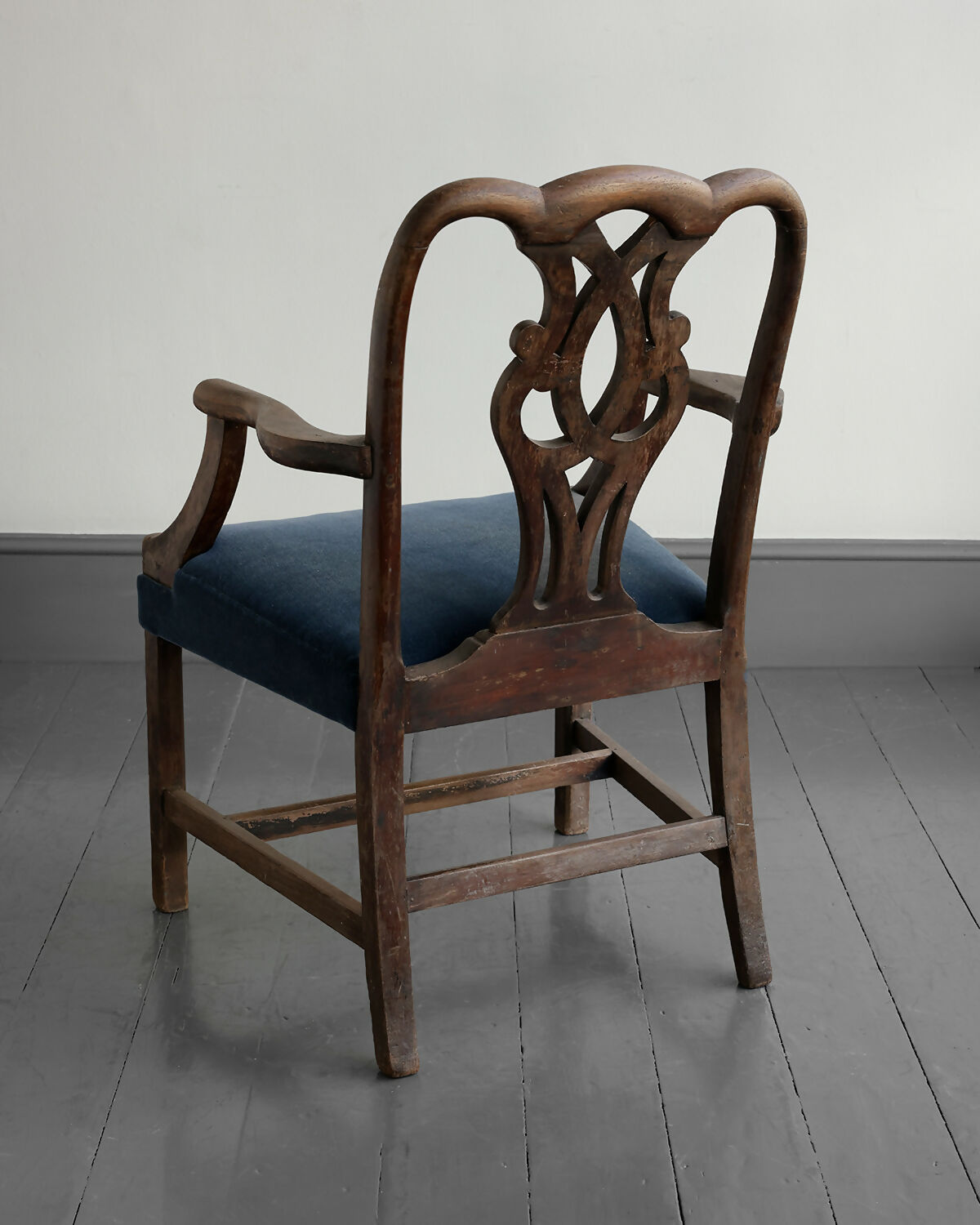 Vintage wooden chair with blue cushion on a gray floor and white wall,available to buy from the-salon.com. SALON curates the finest unique handmade pieces from the interior industry's best makers and brands. Shop luxury furniture, lighting, rugs, art, antiques and vintage pieces and accessories from SALON interior designed rooms. 